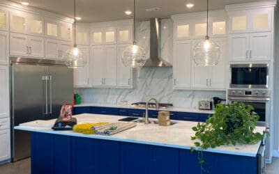 Modern kitchen with marble countertop and blue cabinet island. There's a plant on the island