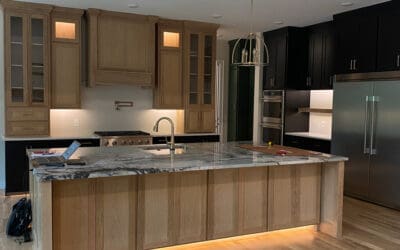 Far view of redone modern kitchen. Island with wooden cabinets, marble countertops and floor lights