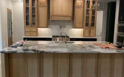 Close view of redone modern kitchen. Island with wooden cabinets, marble countertops and floor lights.